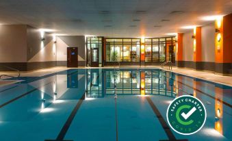 an indoor swimming pool with a safety check sticker on the side , surrounded by a gym area at Claregalway Hotel