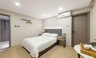 a large , neatly made bed is in a room with wooden floors and a gray headboard at Diamond Hotel (Liancheng Guanzhishan Airport)