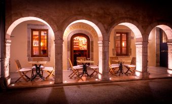 an outdoor dining area with tables and chairs arranged under an archway , creating a warm and inviting atmosphere at L'Hotel de Beaune