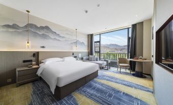 a modern hotel room with a large bed , a couch , and a view of the mountains at xizang hotel  （Norbulingka shop)