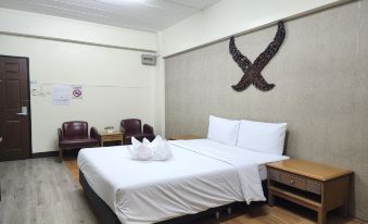 a hotel room with a large bed , white sheets , and a decorative wall design above it at Kim Hotel at Bangplong