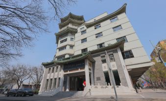 A large, modern building with a stone and brick front entrance in an urban setting at UrCove by HYATT Beijing Forbidden City