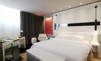 A modern bedroom is furnished with a large bed and a white chair positioned in the center, complementing the art deco style at Metropolo Dahua Hotel Shanghai