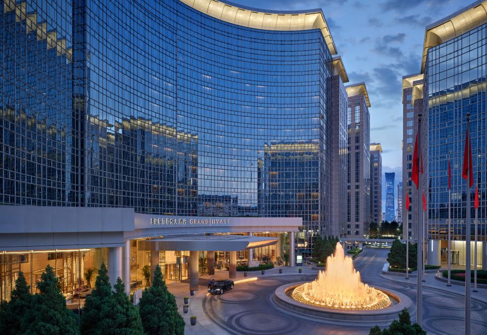 "A large building with an illuminated sign that reads ""hotel"" is visible from the outside" at Grand Hyatt Beijing