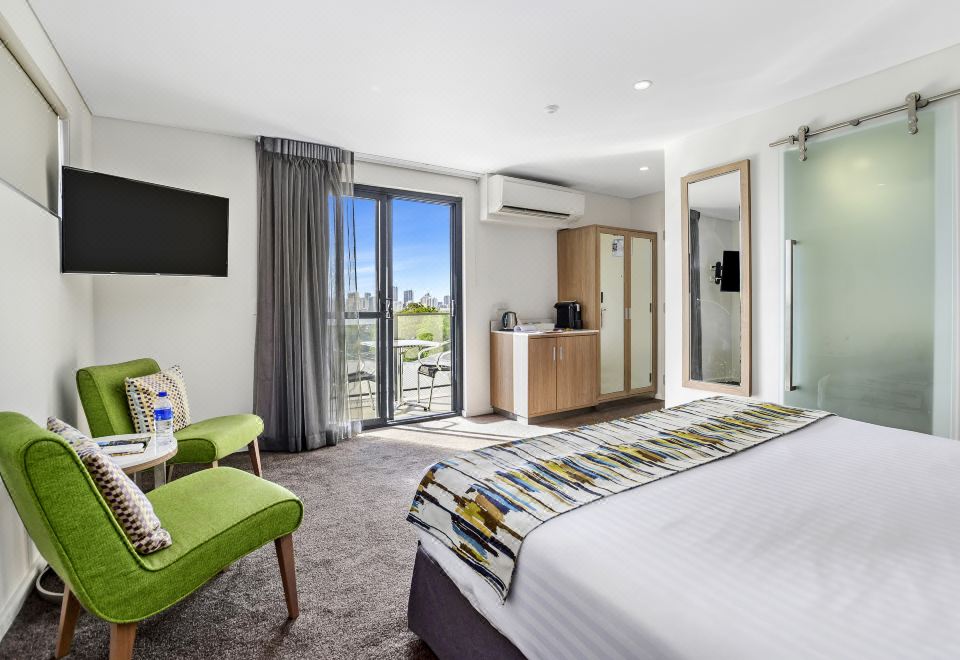 a modern bedroom with a large bed , green chair , and sliding glass door leading to a balcony at Metro Hotel Perth