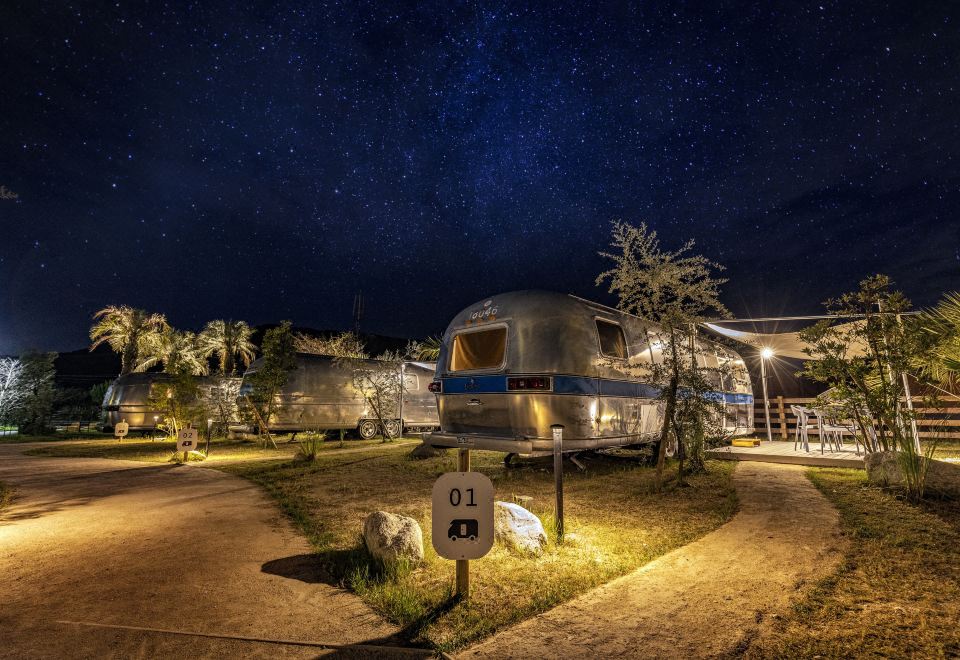 a nighttime scene with a camper parked in a grassy field , surrounded by trees and lit up with lights at The Retreat