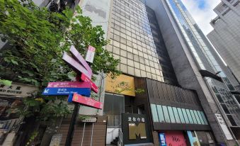 There is a street lined with buildings and signs, including an office block in the foreground at Mini Central