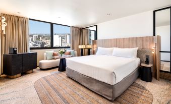 a large bed with white linens is in a hotel room with a view of the city at Pan Pacific Perth