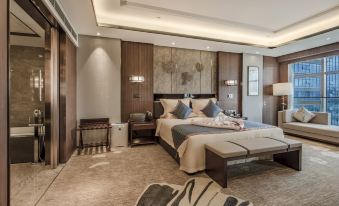 The middle room features a spacious bed with a sitting area and table on each side at Hainan Grand Hotel