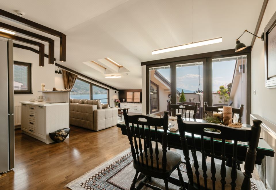 a modern living room with a large window , wooden floor , and various furniture pieces such as a dining table and chairs at Villa Varosh