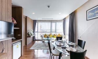 a modern living room with a dining table and chairs , a couch , and a window at Grand Ratchapruek Hotel