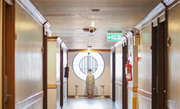 a long hallway with a person standing in the middle , surrounded by doors and windows at Sakol Hotel