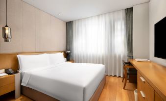 The bedroom features a large bed and a desk in the center, accompanied by two small tables on either side at Jinfan Wanyuan Hotel