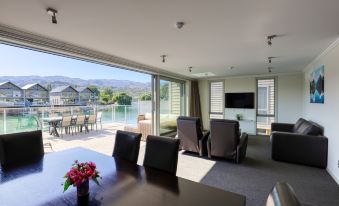 a spacious living room with large windows overlooking a body of water , creating a serene and inviting atmosphere at Marsden Lake Resort Central Otago