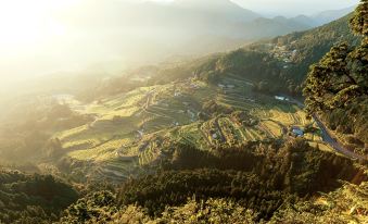 a mountainous landscape with terraced fields and houses nestled in the valley , illuminated by the setting sun at Fairfield by Marriott Mie Kumano Kodo Mihama