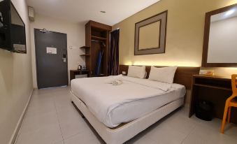 a large bed with white linens is in a room with a brown door and cabinets at Ants Hotel