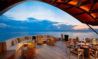 a wooden deck overlooking the ocean , with several chairs and tables placed on it for guests to enjoy the view at The Westin Maldives Miriandhoo Resort