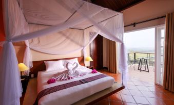 a bed with a white canopy and pink flowers is situated in a room with an open door leading to a balcony at Victoria Nui Sam Lodge
