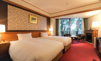 a hotel room with two beds , a window offering a view of trees , and a chair near the window at Nara Hotel