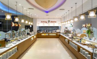 a modern , well - lit restaurant with a long counter and a display of food in the middle at Sand Dunes Chaolao Beach Resort