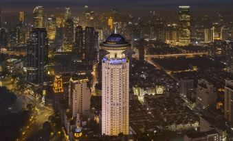 The city skyline is illuminated at night, with buildings in the foreground at Radisson Blu Hotel Shanghai New World