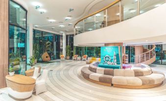 a modern hotel lobby with a large circular seating area , a large fountain in the center , and colorful furniture at Sand Dunes Chaolao Beach Resort