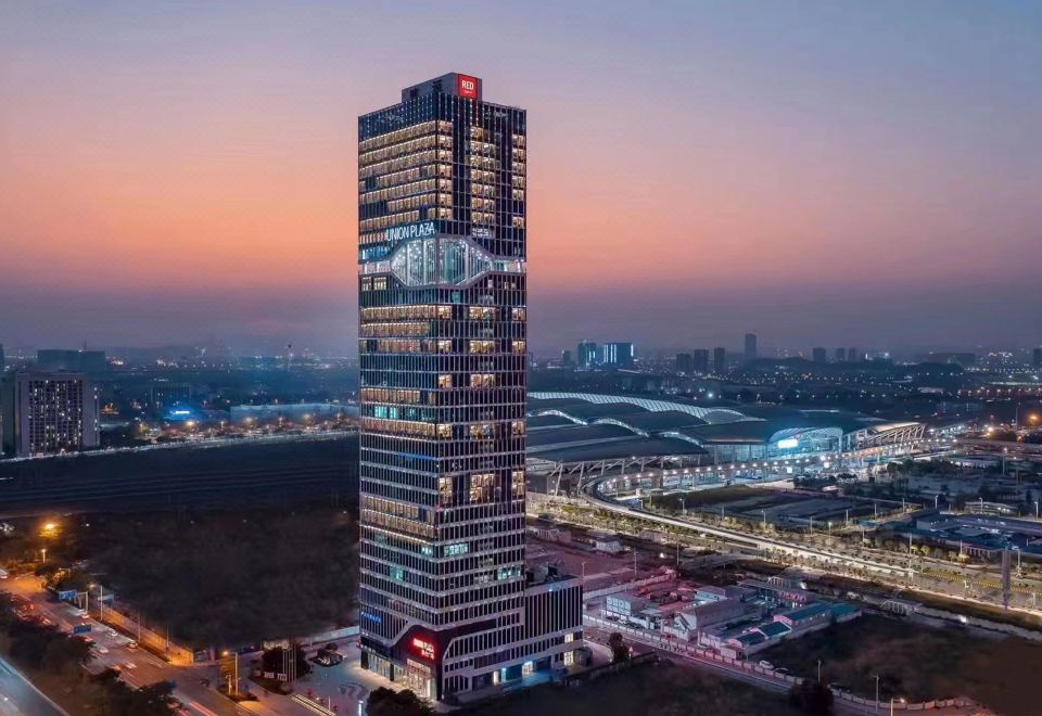 A tall, illuminated building in the city at night, viewed from a distance at Radisson RED Guang Zhou South Railway Station