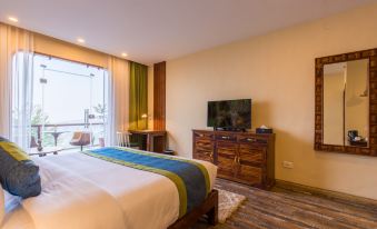 a hotel room with a king - sized bed , a television , and a desk with a computer at Aagantuk Resort