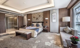 The middle room features a spacious bed with an adjoining sitting area and a table at Hainan Grand Hotel