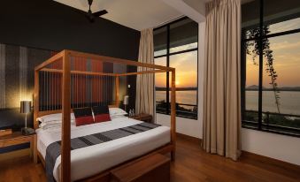 a bedroom with a wooden canopy bed and a view of the ocean through large windows at Heritance Kandalama