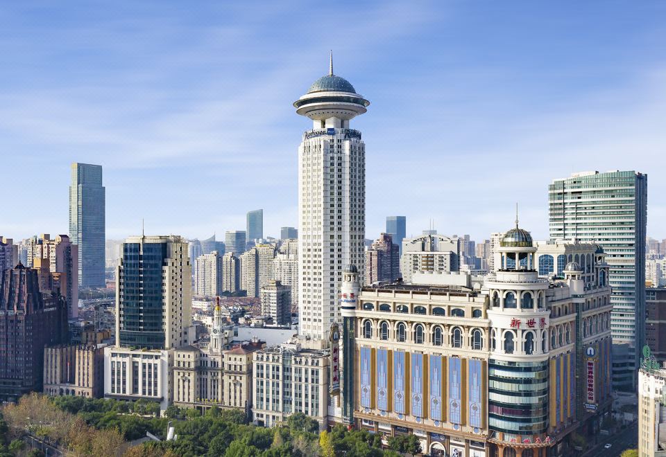 From an aerial perspective, there are multiple prominent buildings in the foreground, one of which stands out due to its significant height at Radisson Blu Hotel Shanghai New World