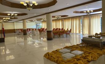 a large , well - lit banquet hall with white floors and red walls , filled with chairs and tables for guests at Sierra Resort powered by Cocotel