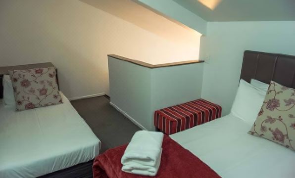 a bedroom with two beds , a red bench , and a white towel on the floor at The Park Hotel Ruapehu