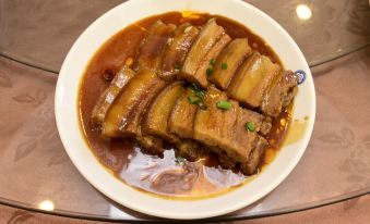 A dish of meat and sauce is placed beside another dish in a white ceramic bowl at Guangmingding Hotel