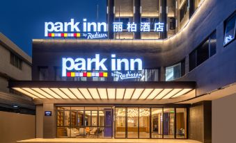 The hotel's front entrance is illuminated at night, displaying a welcoming sign above it at Park Inn by Radisson Guangzhou Railway Station Yuexiu International Congress Center