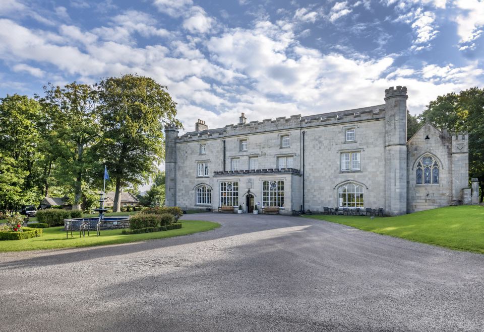 a large white building with a tower and a driveway is surrounded by trees and grass at Thurnham Hall