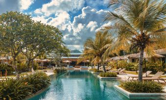 a resort with a large pool surrounded by lounge chairs and umbrellas , providing a relaxing atmosphere for guests at Origin Lombok