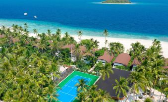 a tropical resort with a tennis court surrounded by palm trees and the ocean in the background at The Westin Maldives Miriandhoo Resort
