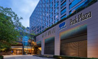 The entrance to a hotel in an urban setting is surrounded by large glass and steel buildings at Park Plaza Beijing Wangfujing