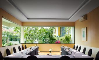 a dining room with a long table set for a formal dinner , surrounded by chairs at El Hotel Malang