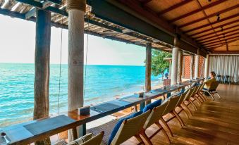 a wooden restaurant with large windows offering a view of the ocean , featuring a dining area with tables and chairs at Kacha Resort & Spa, Koh Chang