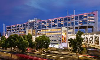 "a large building with the sign "" melbourne "" and other similar buildings , all lit up at night" at PARKROYAL Melbourne Airport