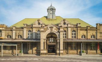 a large stone building with a yellow roof and a clock tower , situated on a city street at 101 Hotel