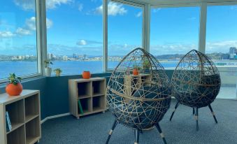 two wicker egg - shaped chairs placed in front of a large window with a view of the city at Novotel Perth Langley
