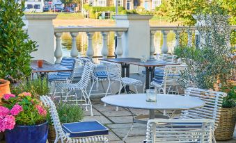 an outdoor seating area with white and blue striped chairs and tables near a body of water at Small Luxury Hotels of the World - the Mitre Hampton Court