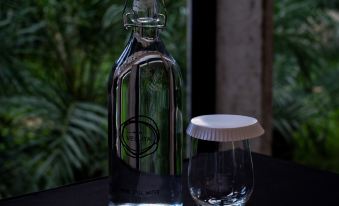 An empty wineglass with water sits on the table next to a bottle and a glass at Hotel Vellita Siem Reap