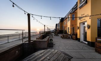 a wooden deck overlooking a body of water , with several people sitting and enjoying the view at The Beaches Hotel