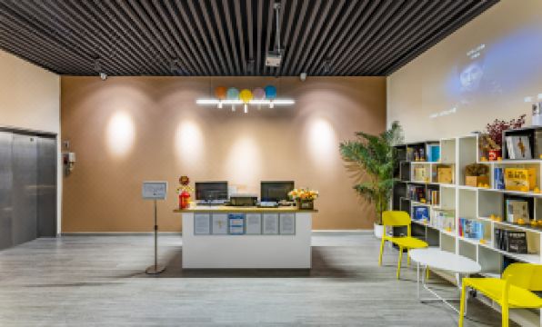 The lobby features a desk and chairs, as well as an adjacent office at Yue City Youth Apartment