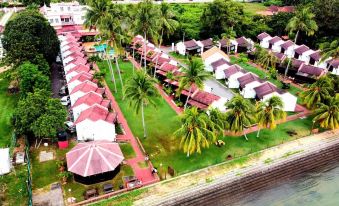 aerial view of a row of houses with red roofs surrounded by palm trees and green grass at Shah's Beach Resort Malacca