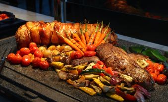 A plate with meat, vegetables, and bread is placed next to another tray that is also filled at Grand Hyatt Beijing